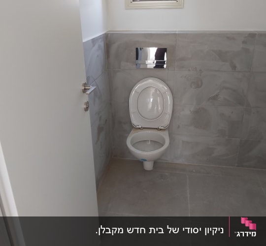 אסלה בחדר שירותים עם קיר אריחים אפור